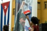 Una mujer cubana ondea una bandera cerca de una fotografía de Fidel Castro en el Cuartel Moncada de Santiago de Cuba el 26 de julio de 2008. Se organizaron numerosas festividades en la ciudad para conmemorar el 55 aniversario del asalto al Cuartel Moncada por Fidel Castro.