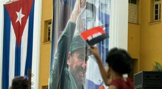 Una mujer cubana ondea una bandera cerca de una fotografía de Fidel Castro en el Cuartel Moncada de Santiago de Cuba el 26 de julio de 2008. Se organizaron numerosas festividades en la ciudad para conmemorar el 55 aniversario del asalto al Cuartel Moncada por Fidel Castro.