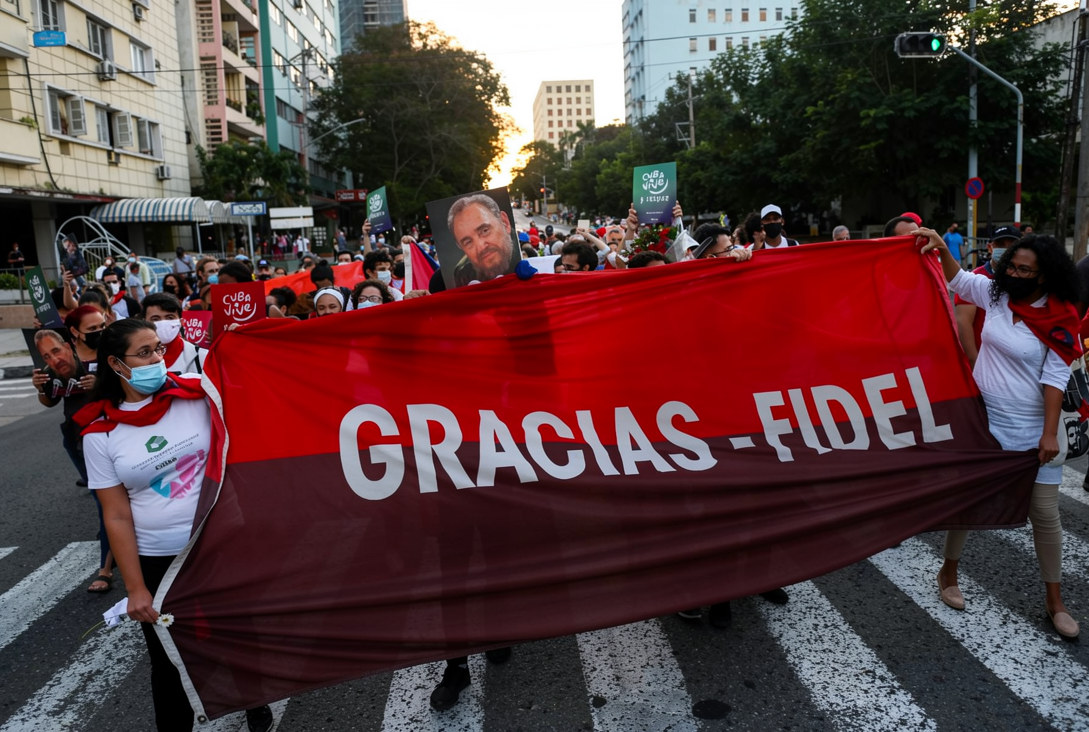 Un grupo de jóvenes camina con pancartas y banderas cubanas por una calle de La Habana con motivo del quinto aniversario del fallecimiento de Fidel Castro, el 25 de noviembre de 2021. (Foto de YAMIL LAGE / AFP)