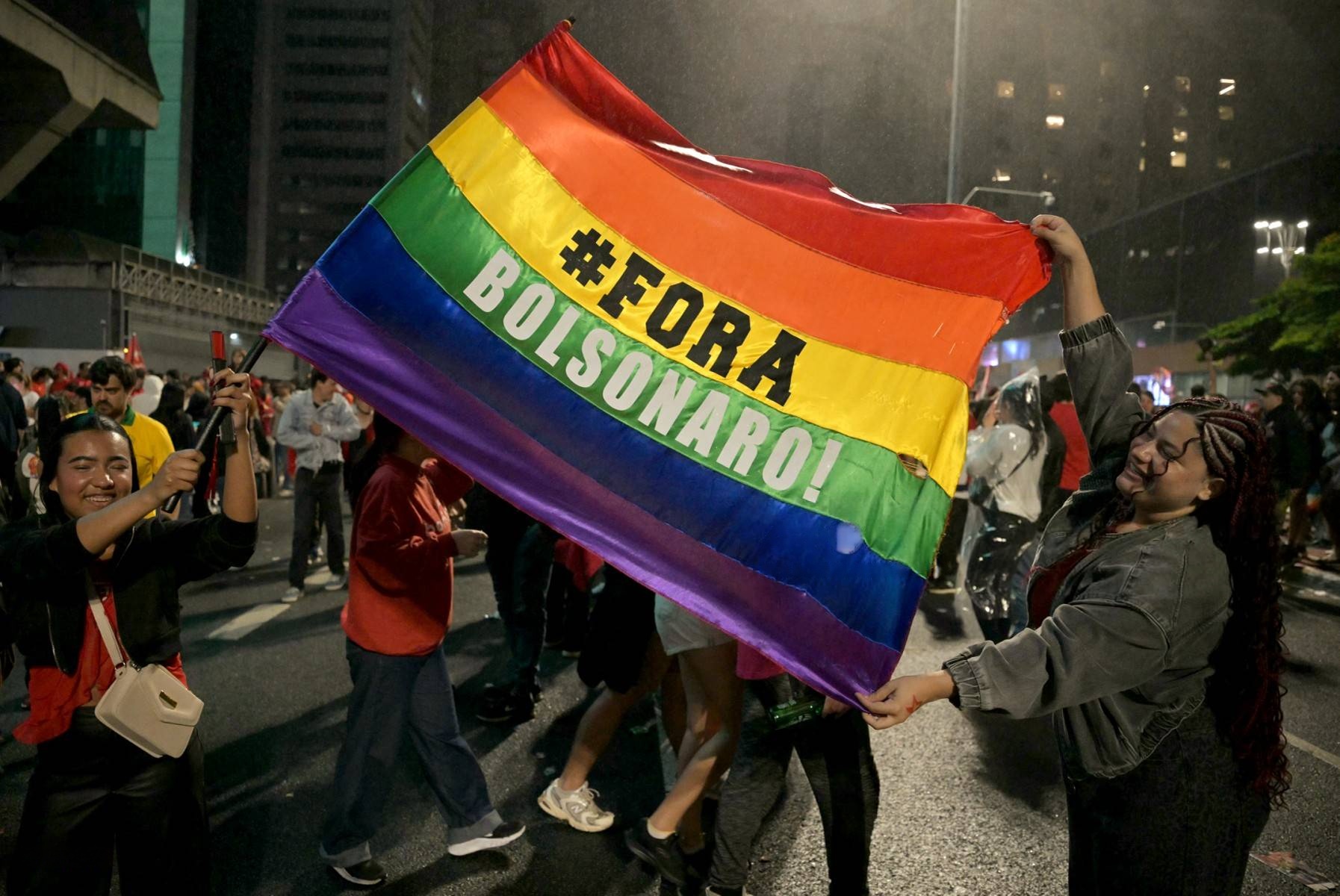 Partidarios del presidente de Brasil y candidato presidencial Luiz Inácio Lula da Silva celebran con una bandera arcoíris que dice «Fuera Bolsonaro» tras la segunda vuelta de las elecciones presidenciales, en São Paulo, Brasil, el 25 de octubre de 2026. (Foto de Nelson ALMEIDA / AFP)